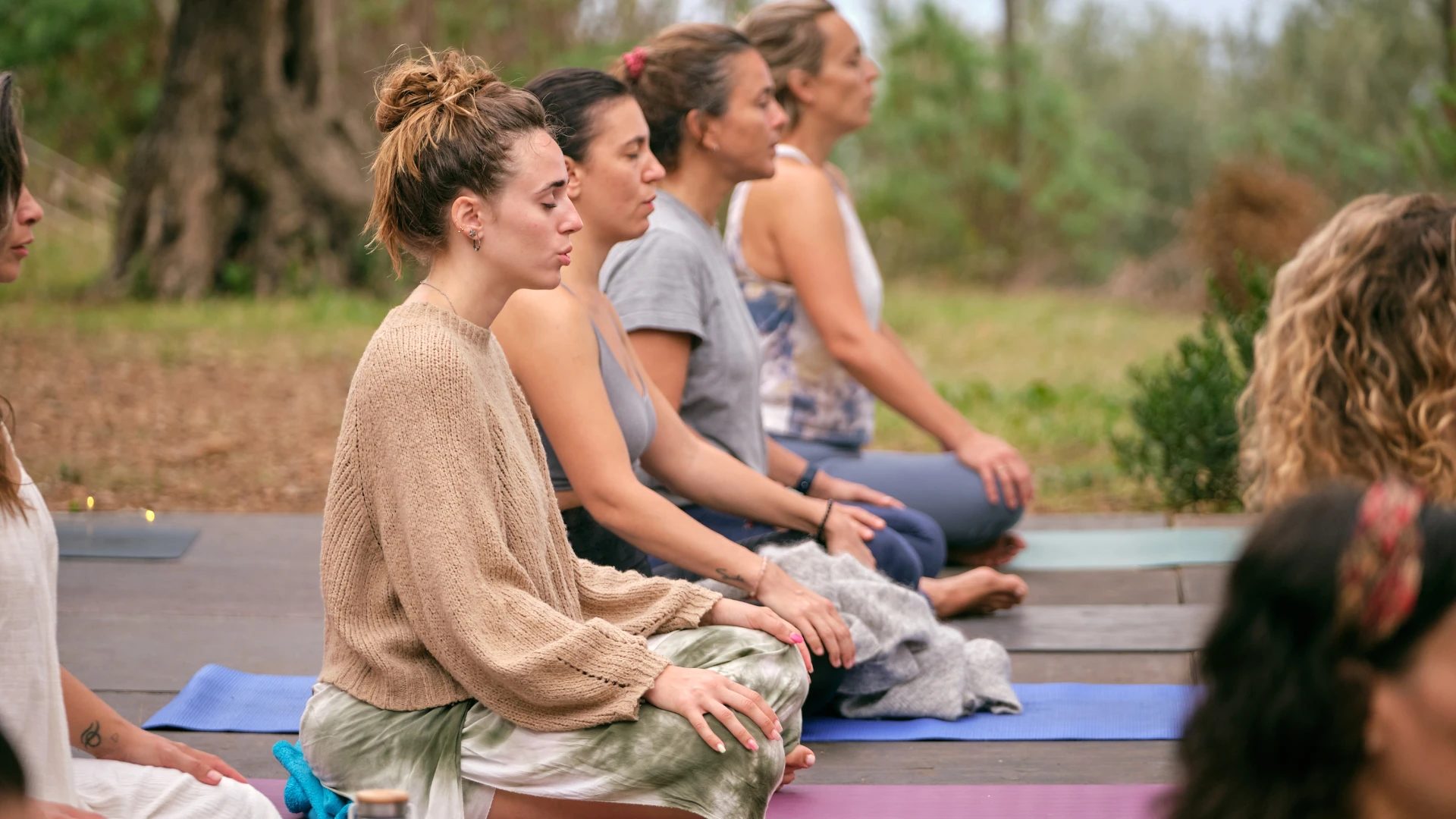 Women meditating together outdoors on yoga mats