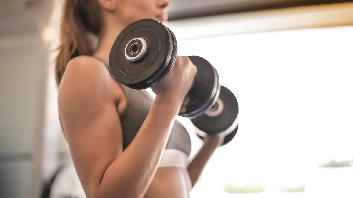 Woman doing dumbbell curls during strength training